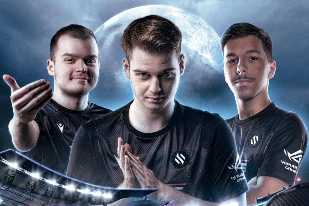 Trois joueurs d'une équipe esportive, vêtus de maillots noirs avec logos de sponsors, posent avec des expressions confiantes et déterminées, sur un fond de ciel nocturne avec la lune en arrière-plan.